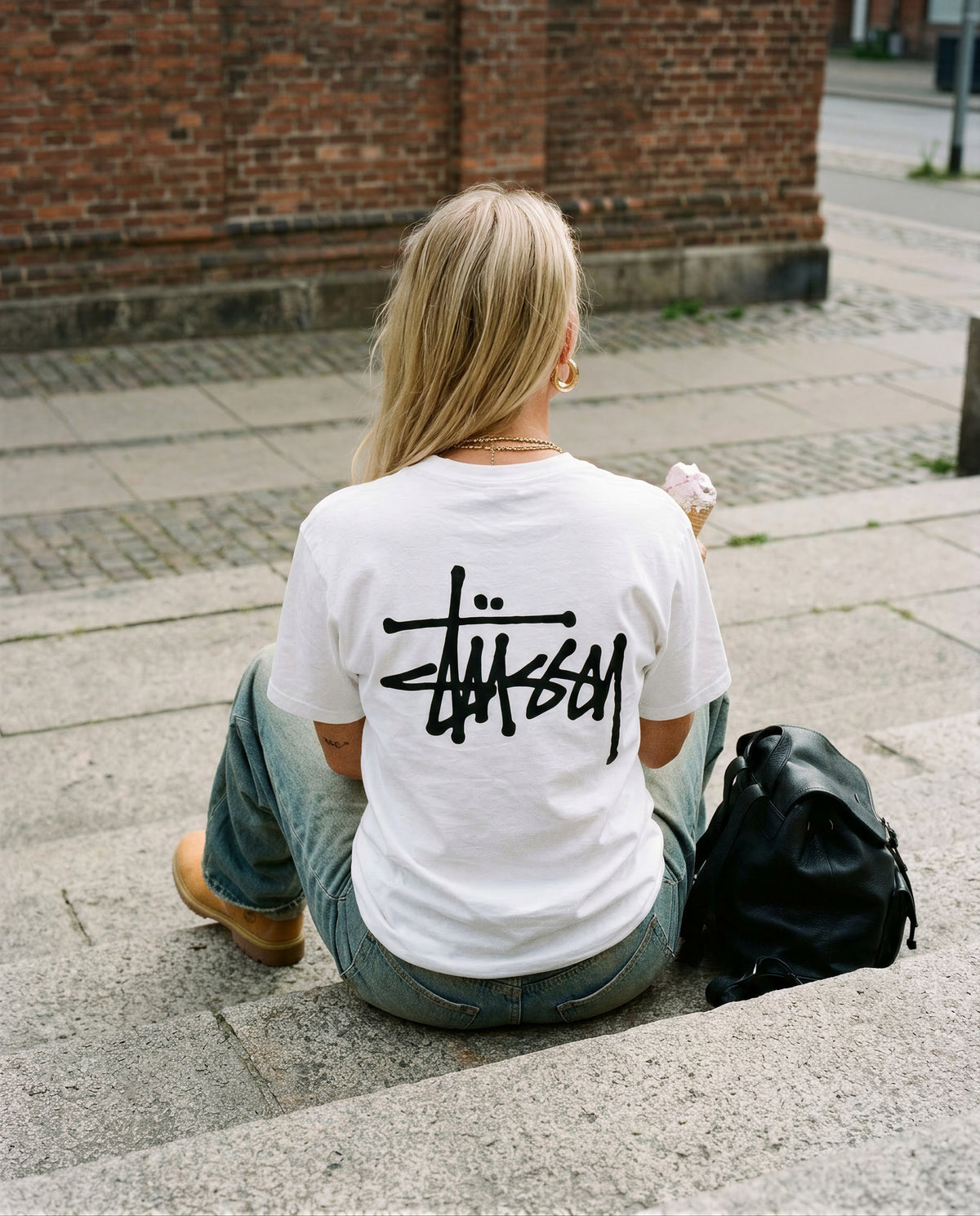 Valkoisen Stussy Basic Tee -paidan takakuva, jossa suuri musta Stussy-graffitilogo selässä.