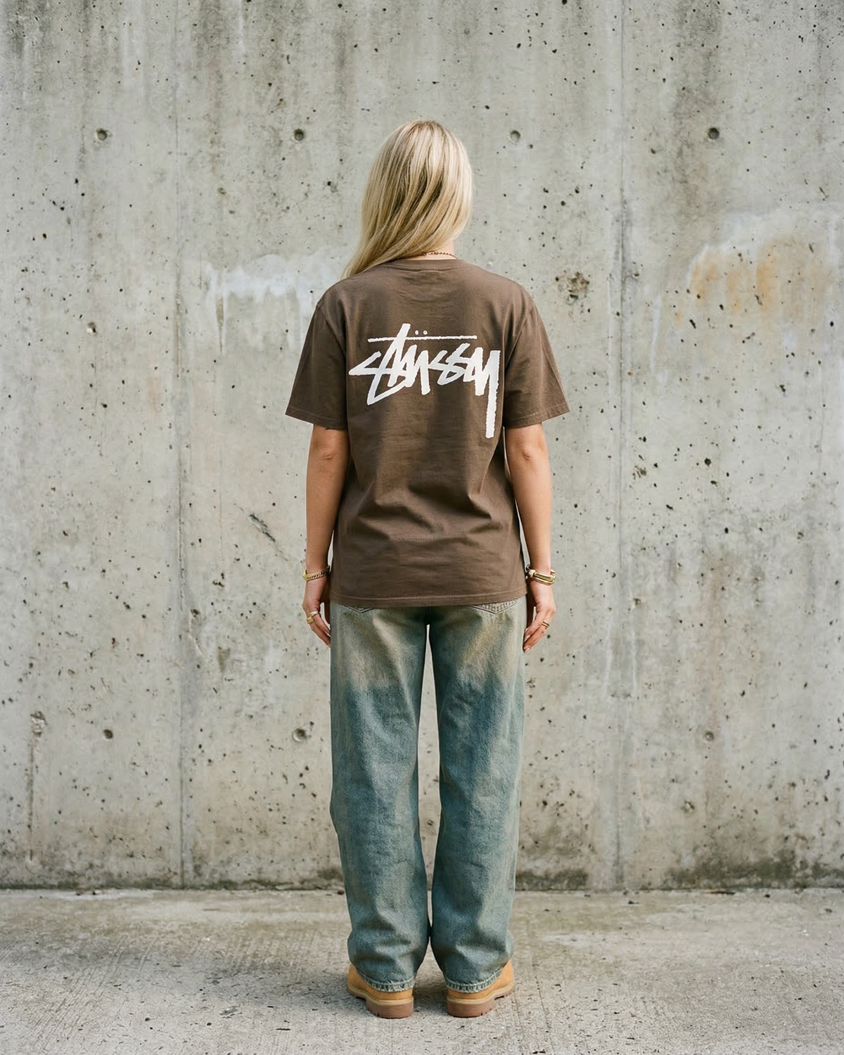 Malli takaa yllään ruskea Stussy Basic Tee Coffee, iso valkoinen Stussy-logo selässä